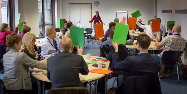 People in a 7 Lenses workshop voting on the importance of different elements with red and green cards.