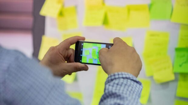 Someone taking a picture of a flip chart covered in post-its with their phone